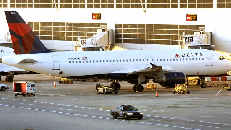 A police car patrols a Delta jet at the Detroit Metropolitan Airport