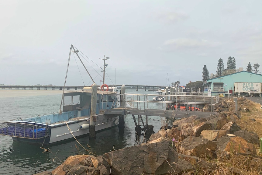 A fishing trawler docked at a pier next to a 'fish co-op' on a lake.