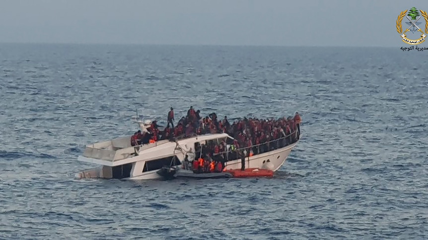 People in a dinghy, rescue migrants from a sinking boat