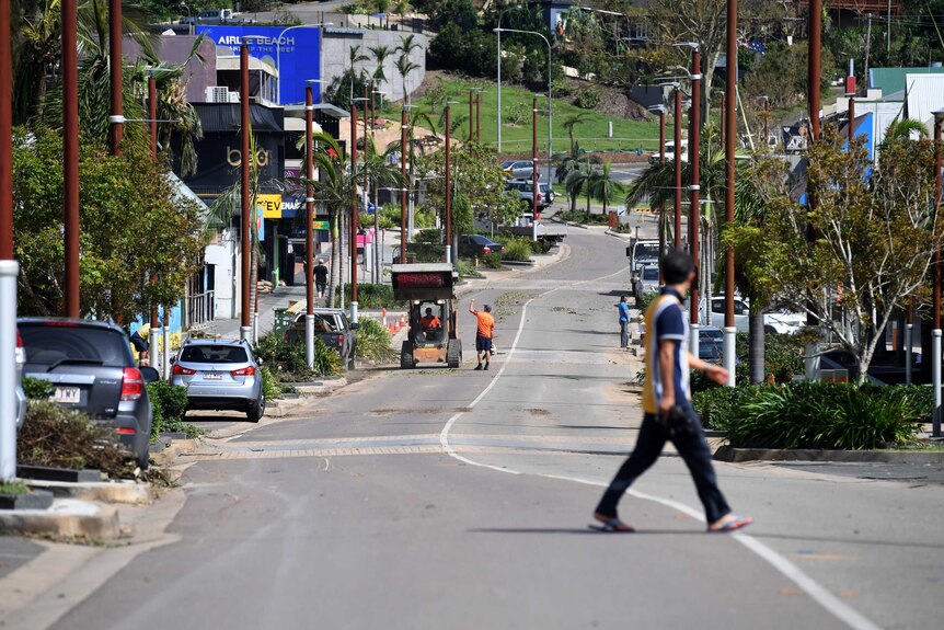 People walk on the main street of Airlie beach after Cyclone Debbie smashed the reason.