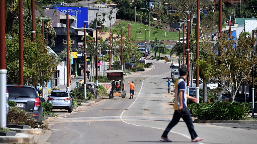 People walk on the main street of Airlie beach after Cyclone Debbie smashed the reason.