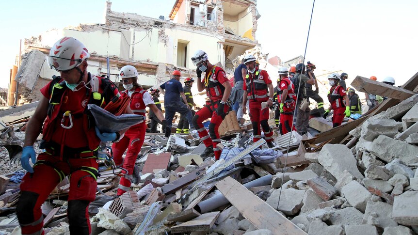 Rescue workers walk through rubble.