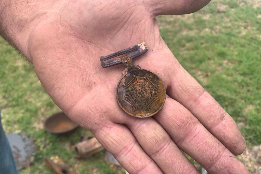 A hand cradles a burnt Country Fire Service medal