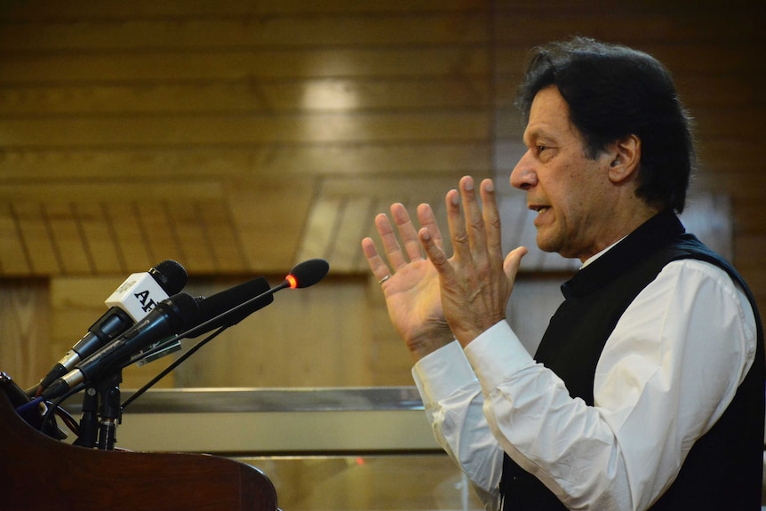 A profile shot of Pakistan's prime minister Imran Khan, gesturing with his hands as he speaks to a crowd on Independence Day