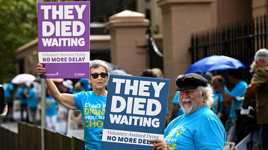 Two older people holding up placards. 