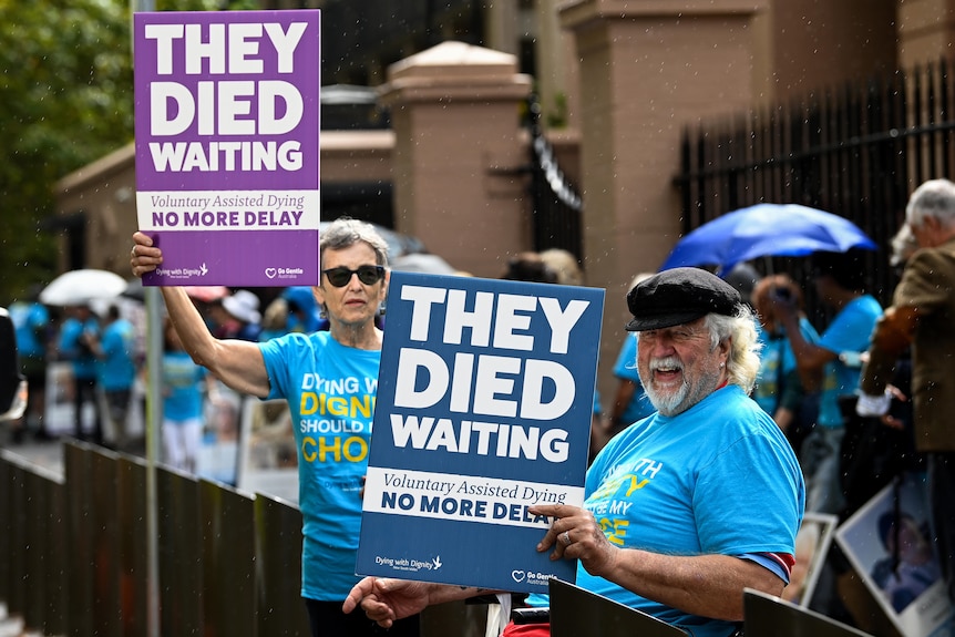 Two older people holding up placards. 