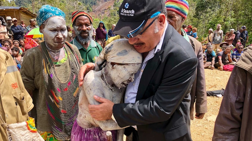 PNG Prime Minister Peter O'Neill hugs a crying woman painted in white body paint