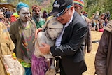 PNG Prime Minister Peter O'Neill hugs a crying woman painted in white body paint