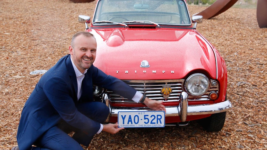 Chief Minister Andrew Barr with a number plate reading 'Canberra - the bush capital'.