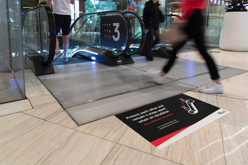 A floor sticker in a Westfield shopping centre which advises people to remain 4 steps apart when on the escalator
