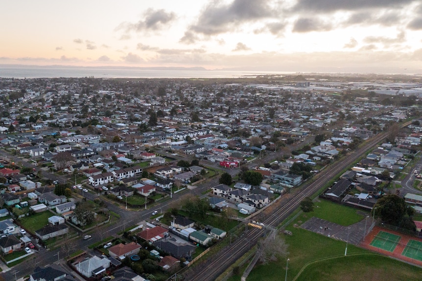 A drone shot shows suburban blocks in South Auckland. 