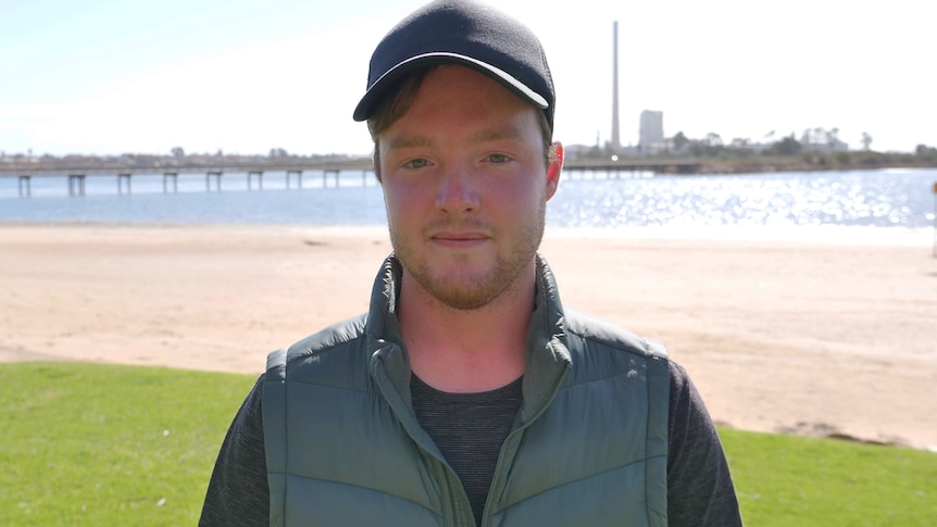 a man stands in front of a beach with a lead smelter in the background