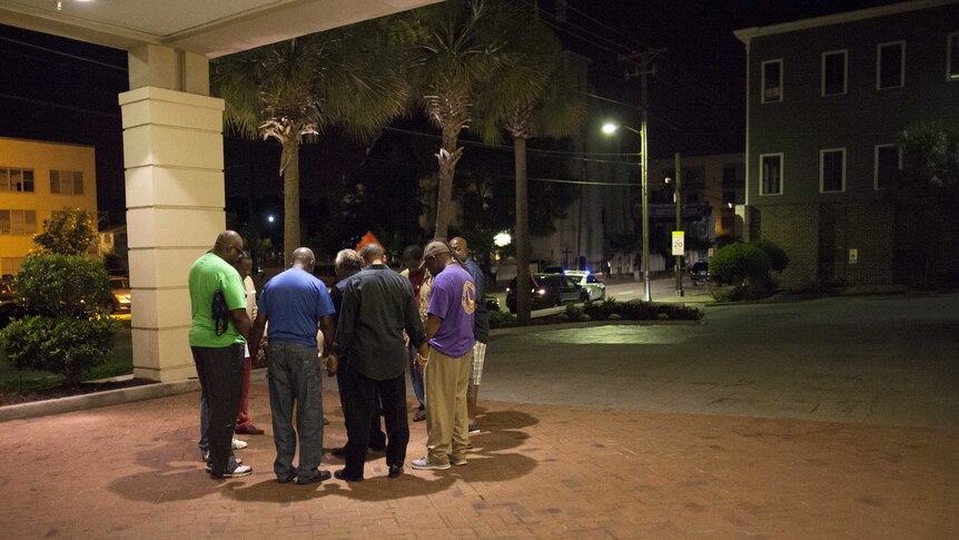 A small prayer circle forms near the scene of a shooting in Charleston