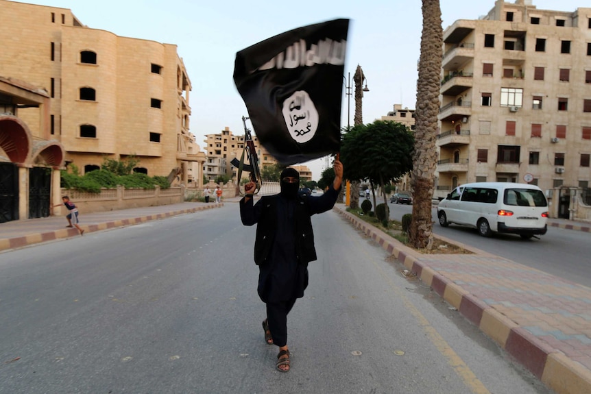 A member loyal to the Islamic State in Iraq and Syria waves an ISIS flag in Raqqa, Syria