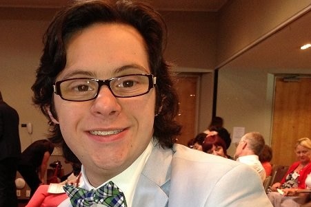 A close up photo of a man wearing a bow tie and silver jacket.