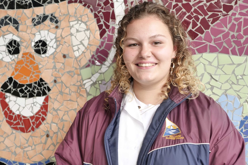 A portrait of a female high school student in front of a mosaic
