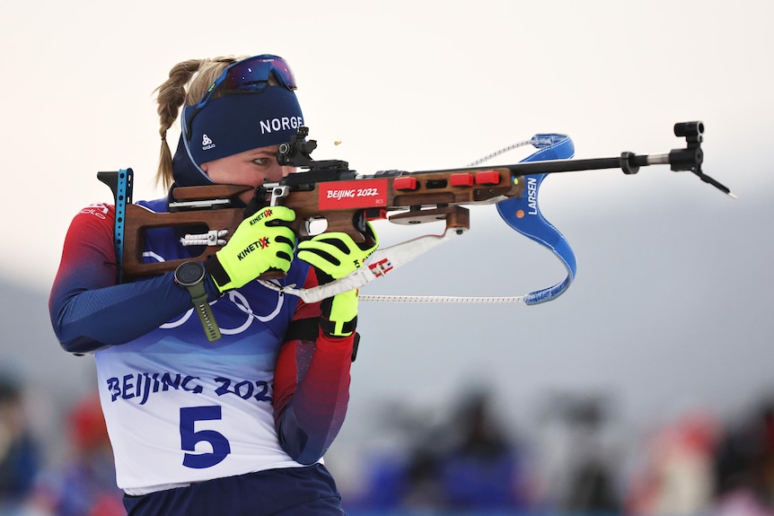 Marte Olsbu Roeiseland looks down the barrel of her gun while warming up before the biathlon