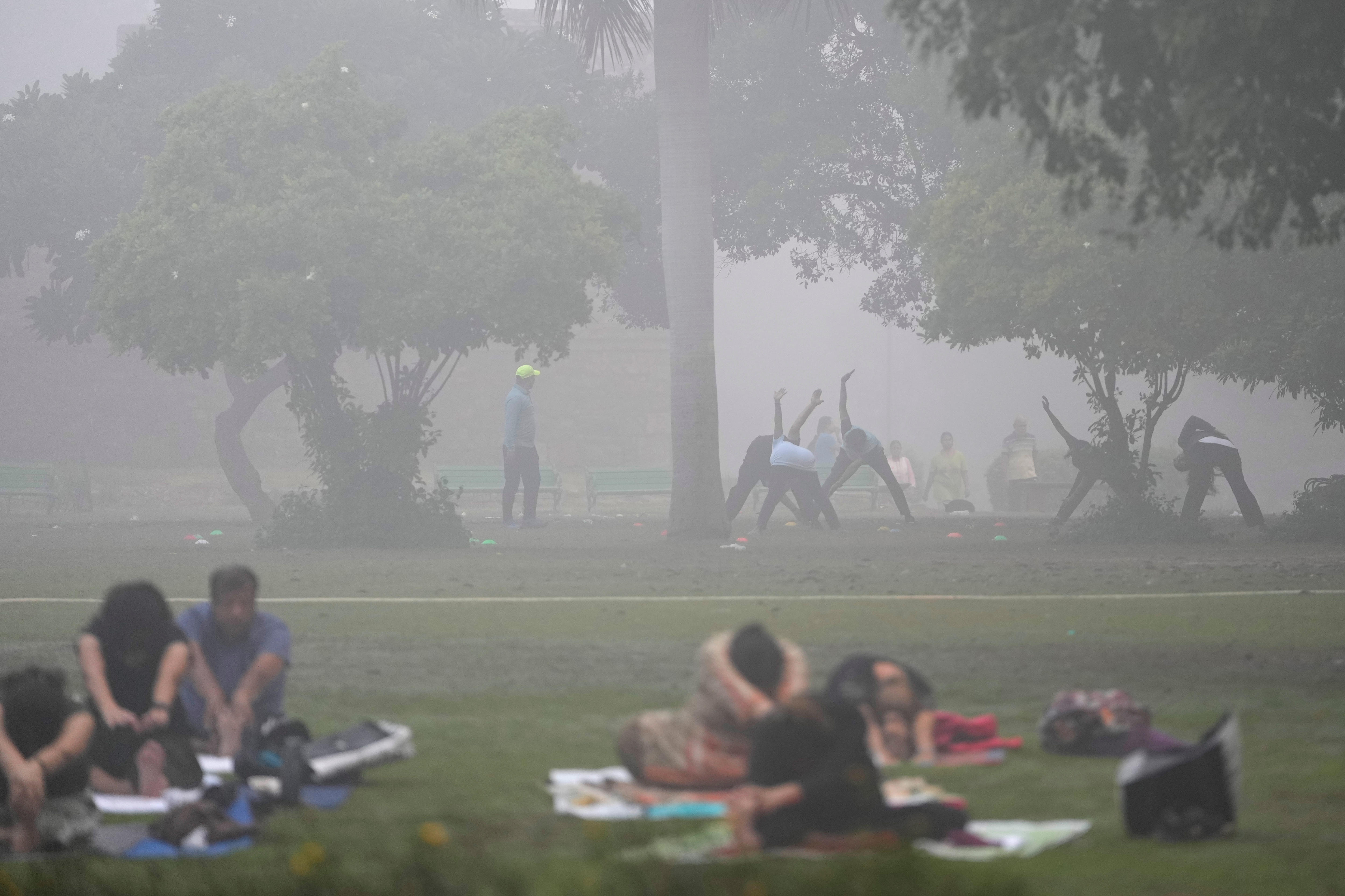 People do yoga early morning at a park in Delhi enveloped by smog