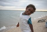 A photo of a  small Indigenous boy fishing on the beach at Cullen Point.
