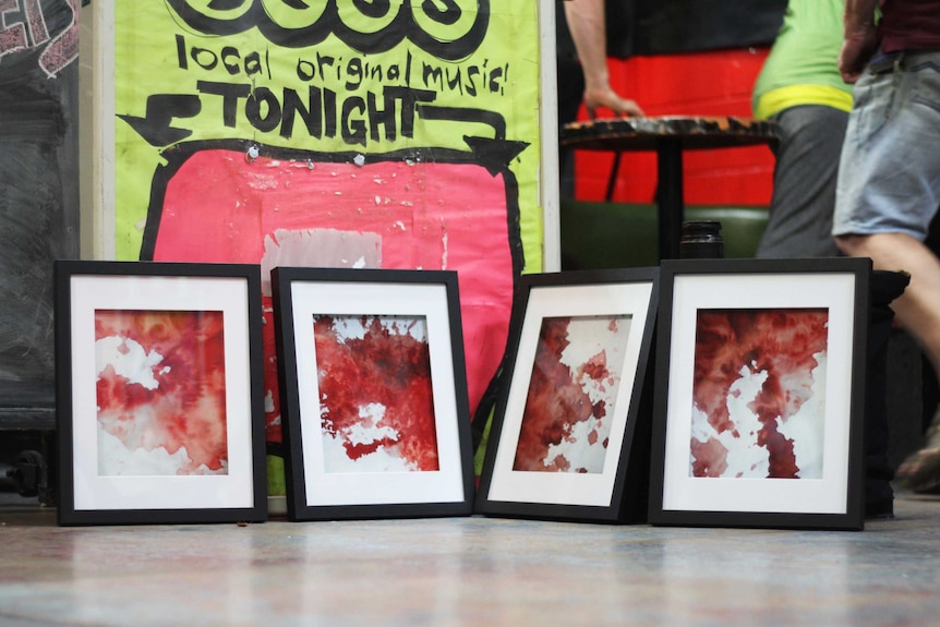 Four framed images of blood splattered on white sheets.