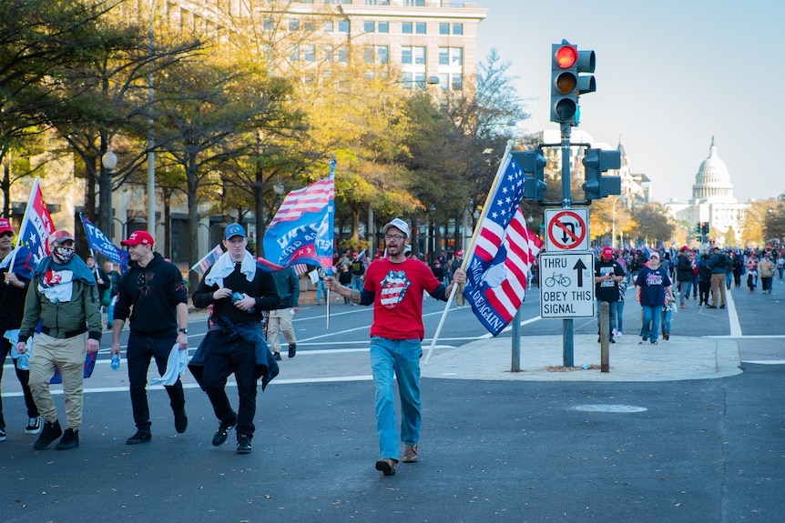 men holding Trump flags walk out in front of groups of people in Washington DC