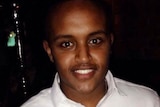 A headshot of a young man with dark skin, smiling for the camera.