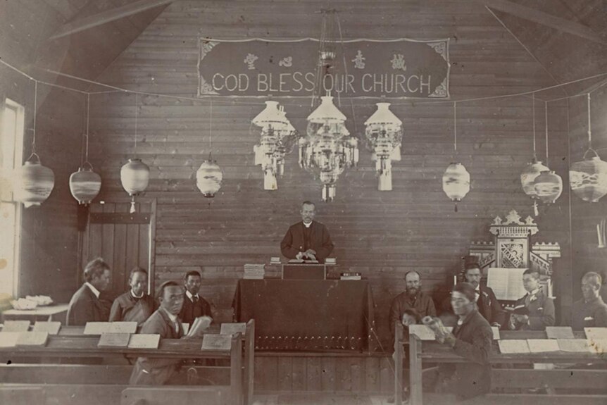 Chinese men sitting in the interior of a church.