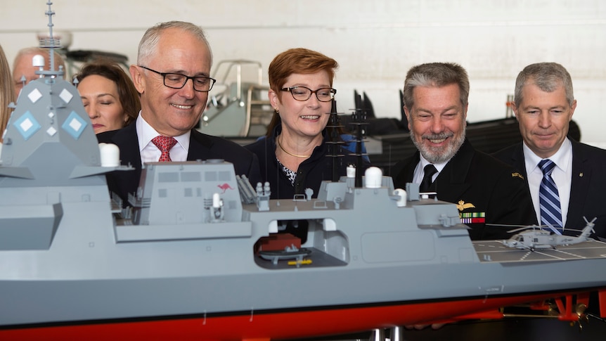 Four people including then prime minister Malcolm Turnbull look at a model of a navy boat