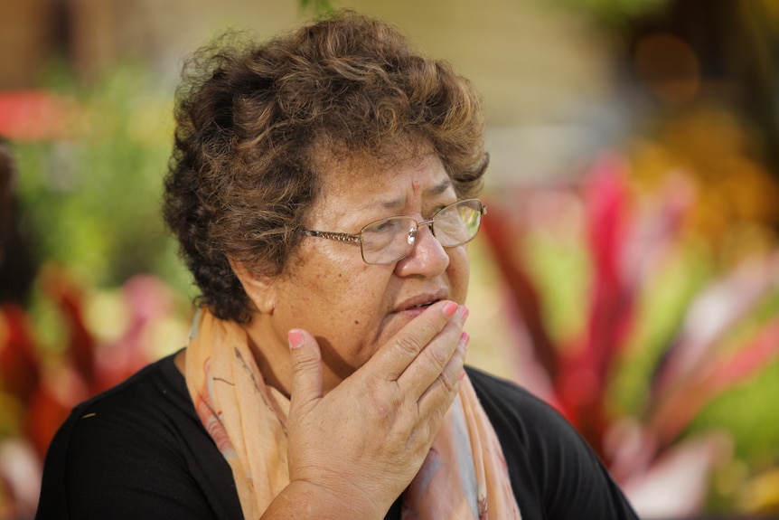 A woman wearing a black top and a yellow scarf.