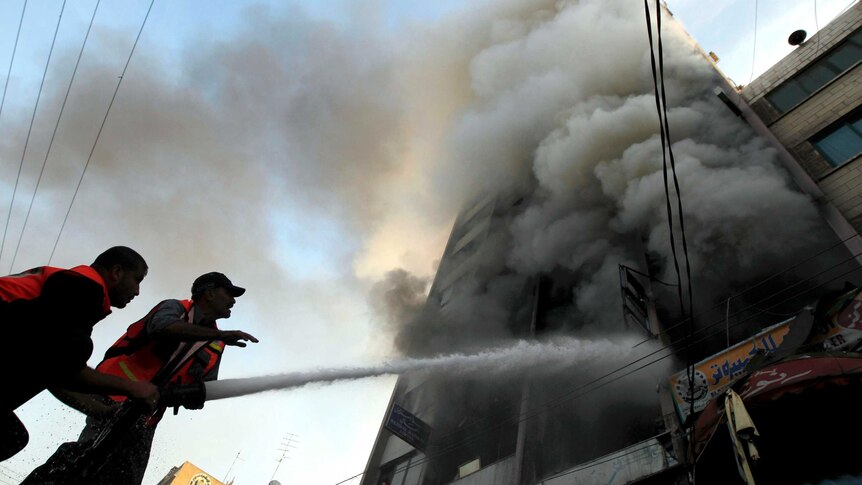 Firefighters extinguish a fire at the Gaza City tower housing Palestinian and international media.