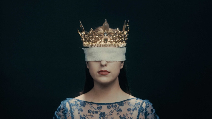 A women wearing a crown and with gauze covering her eyes.