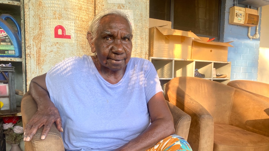 aboriginal woman in blue shirt sitting on brown armchair