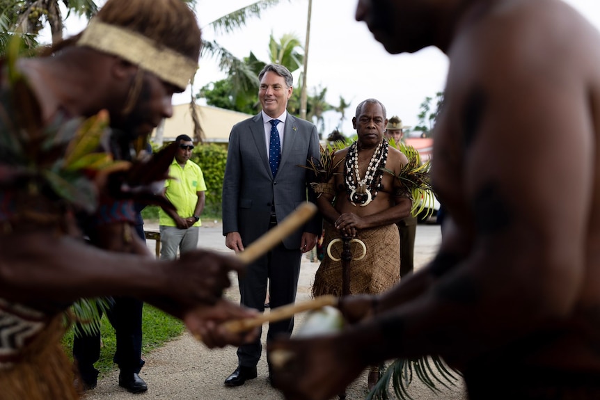 ni-Vanuatu chiefs walking alongside an Australian man, Richard Marles, in a traditional welcome ceremony