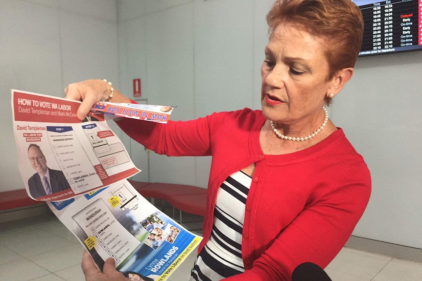 Pauline Hanson holds up Labor and Liberal how to vote flyers
