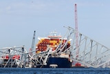 A container ship beneath a collapsed metal bridge