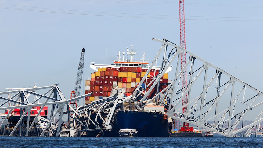 A front on shot of the container ship with giant strips of the metal bridge collapsed on top