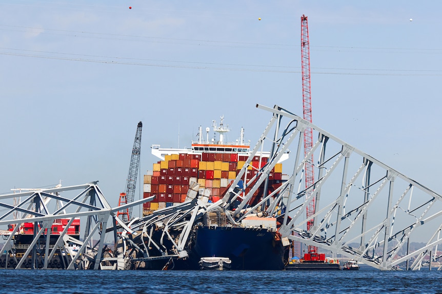 A front on shot of the container ship with giant strips of the metal bridge collapsed on top