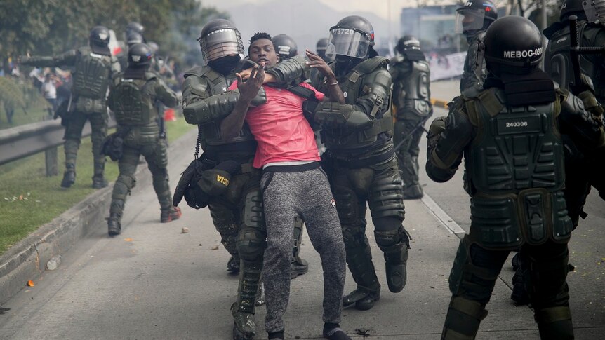 Police arrest a protesters in a street in Colombia.