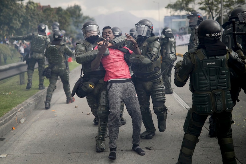 Police arrest a protesters in a street in Colombia.