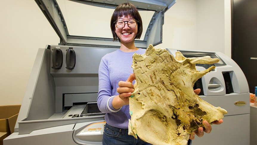 ANU PhD student Yuzhi Hu holding a large 3D printed fish fossil.