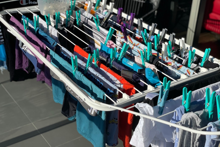 A range of underwear and t shirts pegged onto a portable clothes rack on  apartment balcony.