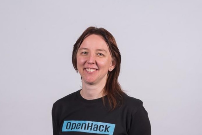 A middle-aged woman wearing a black T-shirt and with dark hair smiles and looks at the camera.