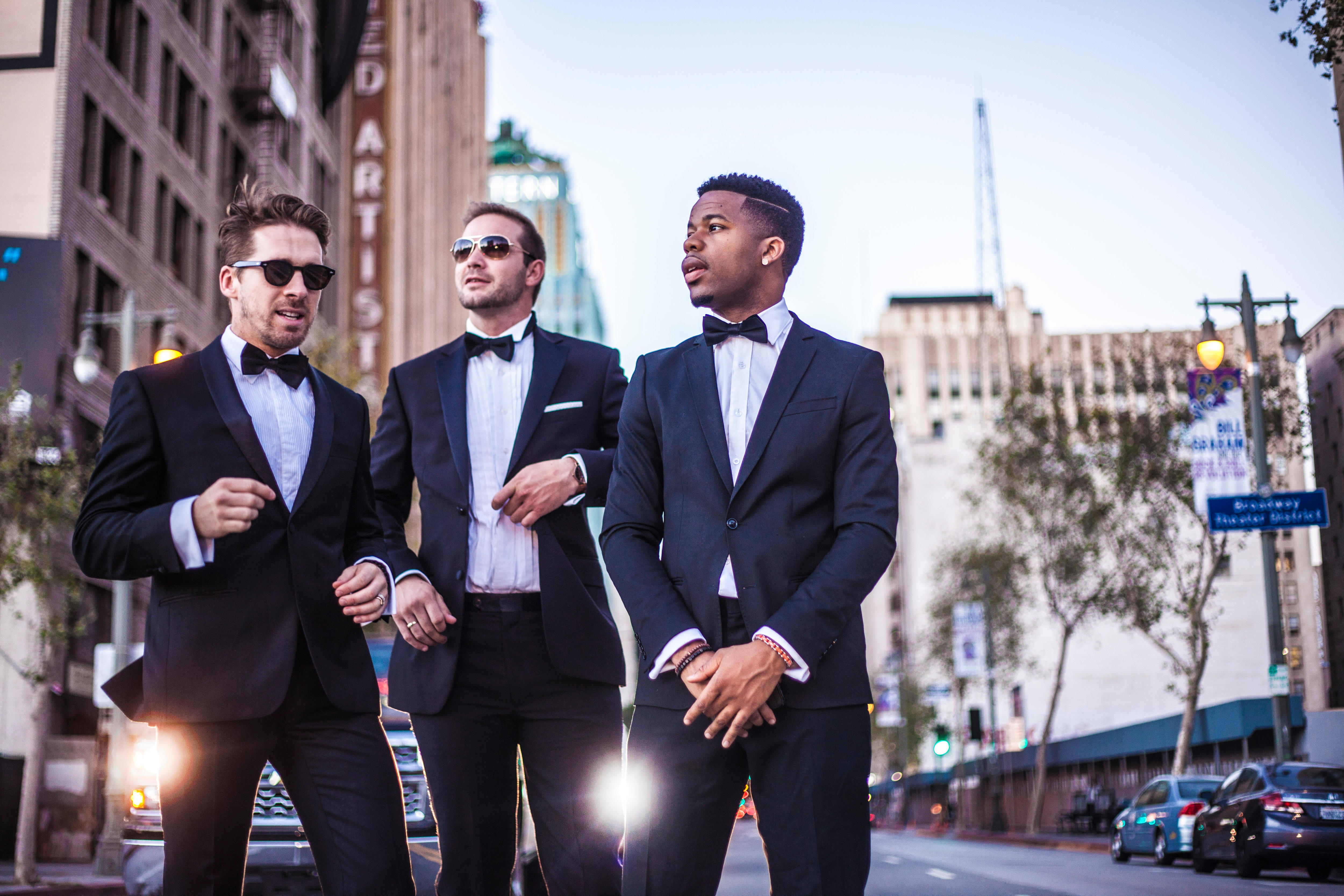 image of three men in suits standing infront of a city