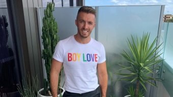 man wearing a white shirt which reads boy love