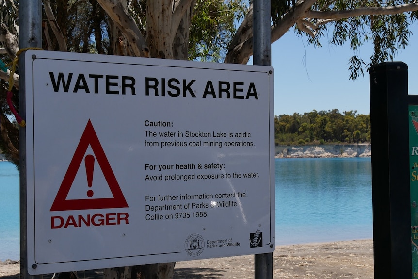 A water risk sign stands in front of a lake