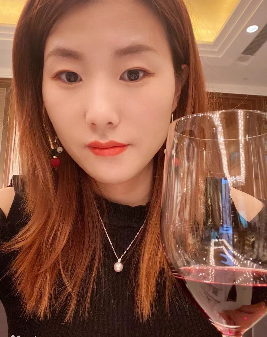 一个年轻的中国女性举着葡萄酒杯。