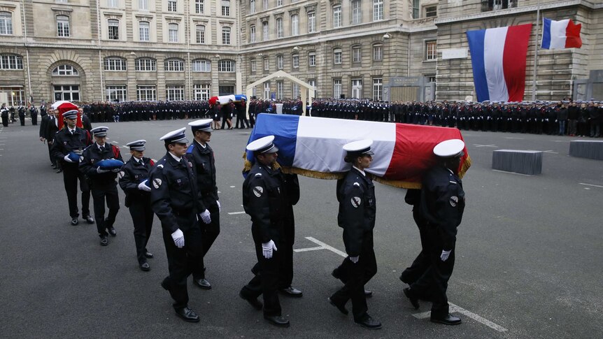 Police officers carry coffins of police officers draped in French flag