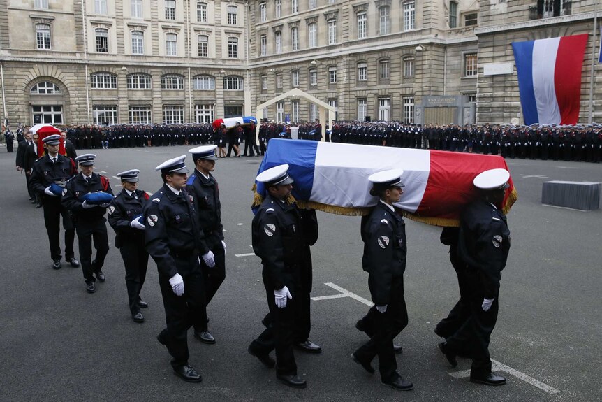 Police officers carry coffins of police officers draped in French flag