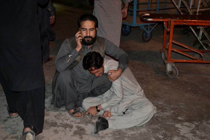 A man comforts another mourning the death of a relative at a hospital in Quetta after the explosion.