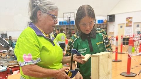 an elderly woman showing a younger woman how to make a wooden box